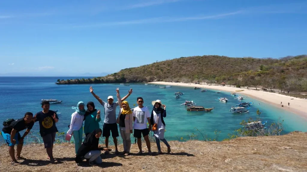 Wisatawan berfoto dengan latar Pantai Pink Lombok dalam Paket Tour Pantai Pink Lombok 1 Hari