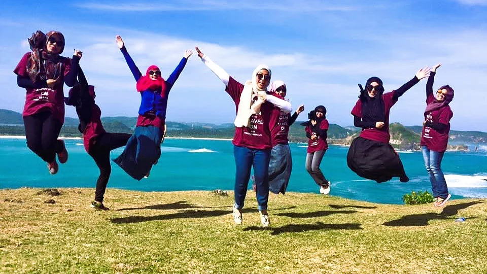 Tamu Lombok Travelmate melompat di Bukit Merese dengan latar Pantai Tanjung Aan
