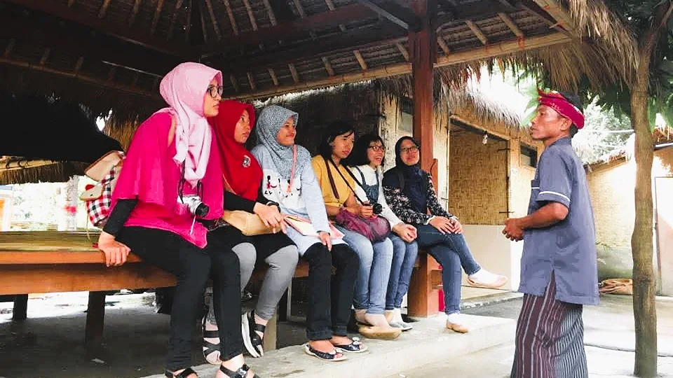 Tamu Lombok Travelmate mendengarkan pemandu lokal di Desa Sade, Lombok