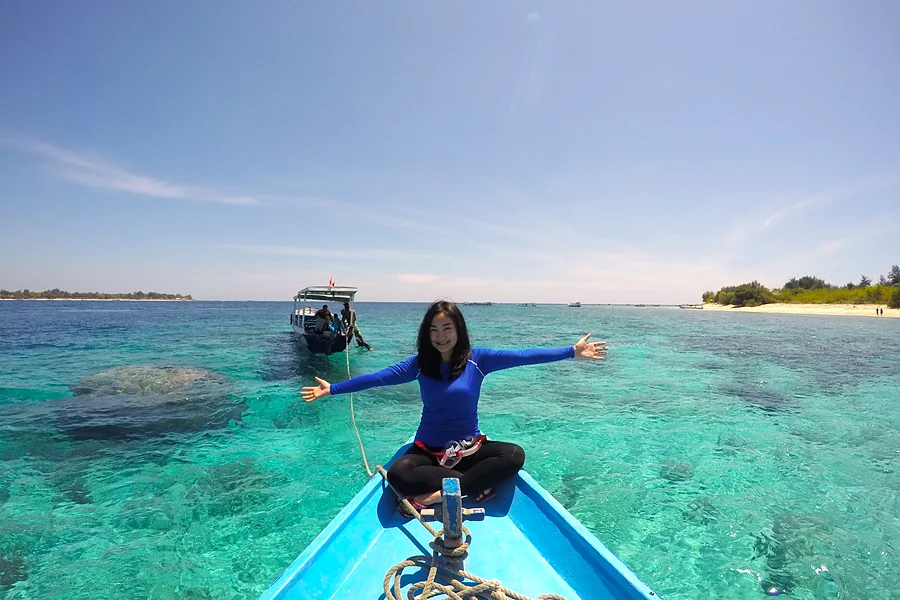 Duduk di haluan boat di atas laut toska Gili, Paket Tour Lombok 4 Hari 3 Malam E